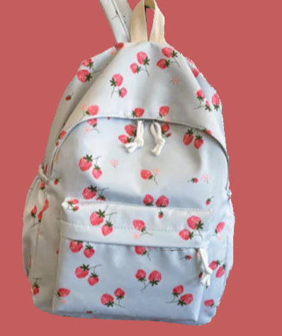 Person wearing a light blue backpack with red floral patterns indoors.