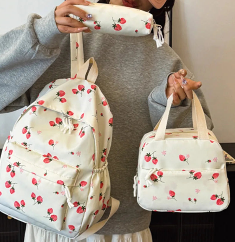 Person holding a floral backpack and lunch bag in a room setting.