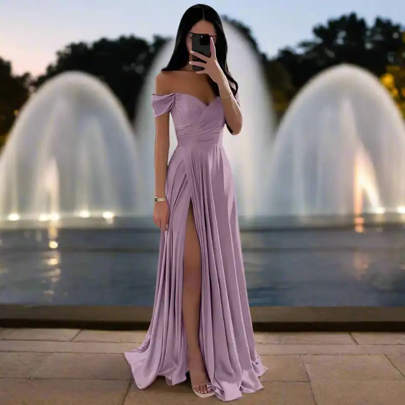 Lavender off shoulder satin gown with pleated skirt and thigh-high slit, styled in front of a fountain for formal occasions.