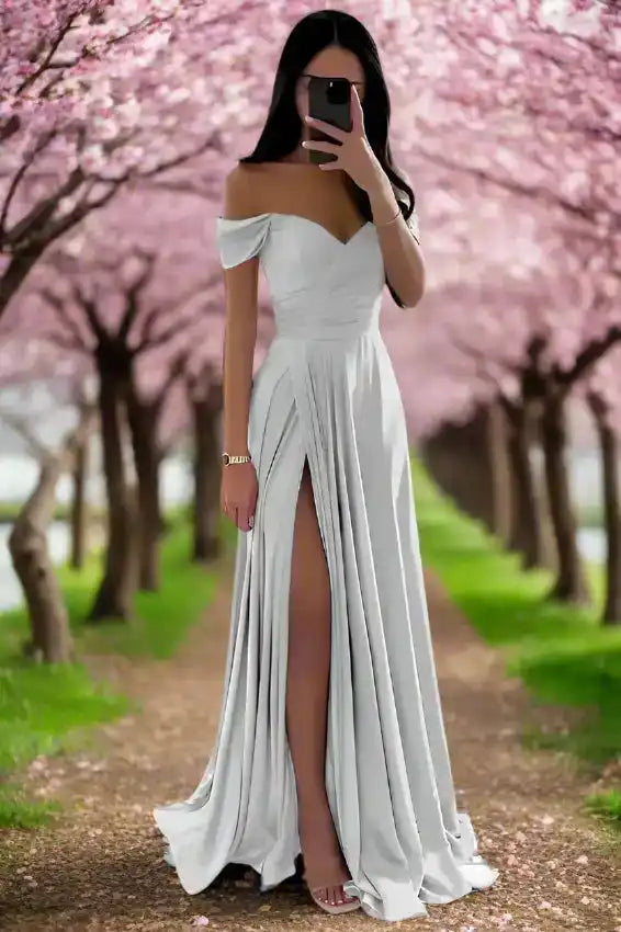 White off shoulder satin evening gown with pleated A-line skirt and high slit, perfect for spring weddings or formal occasions.