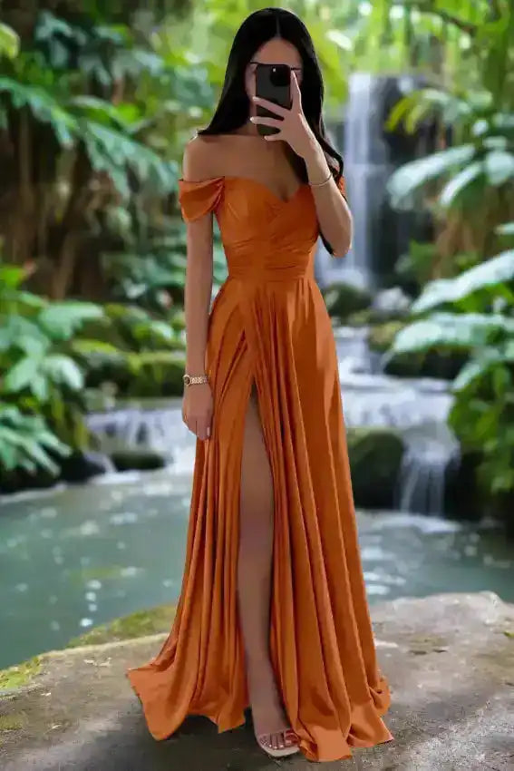 Burnt orange off shoulder satin gown with pleated A-line silhouette and high slit, ideal for autumn weddings or formal events.