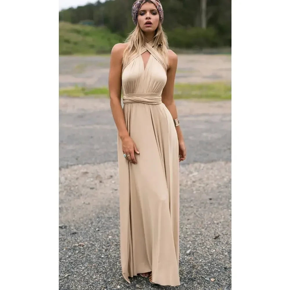 Woman wearing a long beige dress standing on a gravel road with greenery in the background